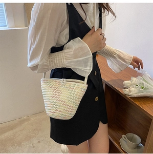 Détail du sac seau tissé à la main avec coutures colorées et fermeture boutonnée sur modèle