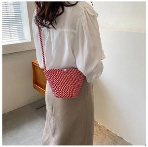 Détail du sac seau tissé à rayures rouges et blanches avec fermoir perle et bandoulière
