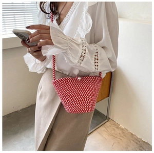 Détail du sac seau tissé rouge et blanc avec fermoir perle et fine bandoulière tressée