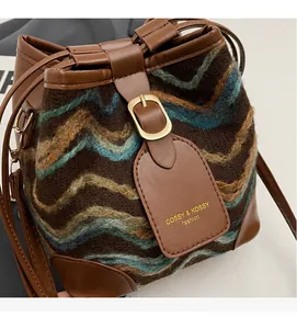 Close-up of bohemian knit bucket bag with brown leather details and golden hardware