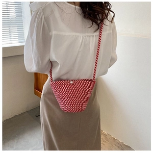 Détail d'un sac seau en paille à rayures rouges et blanches avec fermoir perle