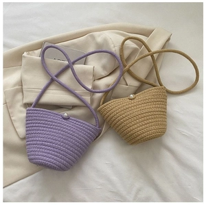 Détail de sacs seaux tissés en violet et kaki avec un élégant bouton en perle décoratif