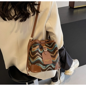 Detail of bohemian bucket bag with woven wavy patterns and brown leather strap