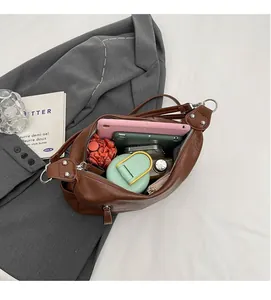 Vue de dessus montrant le grand intérieur du cabas en cuir marron avec des accessoires