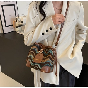 Detail of knit bucket bag with wave texture, brown leather trim and drawstring closure