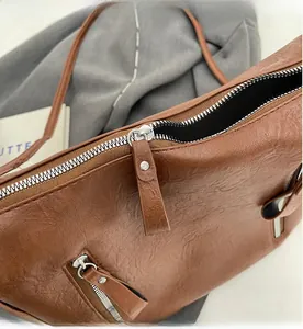 Détail de la fermeture éclair lisse et du cuir marron texturé sur un sac fourre-tout
