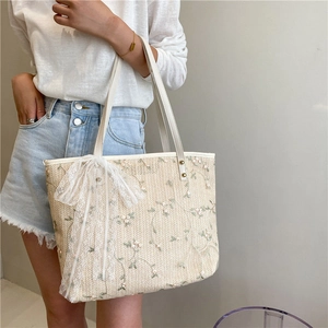 Straw tote bag with floral embroidery and white lace bow in a fresh summer style