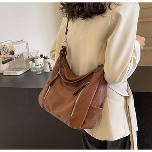 Détail du sac hobo en cuir marron vintage avec poches zippées et bandoulière réglable