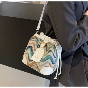 Detail of bohemian bucket bag with woven wavy pattern and white leather trim on shoulder