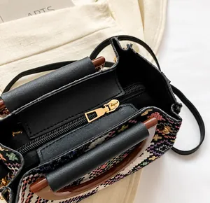 Top view of woven ethnic handbag showing smooth black zipper and brown leather handles