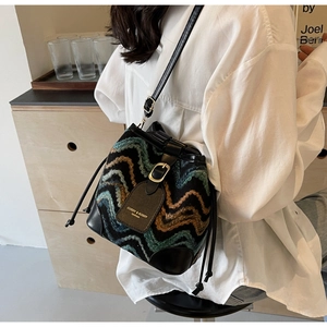 Detail of bohemian bucket bag featuring wave embroidery and leather drawstring closure