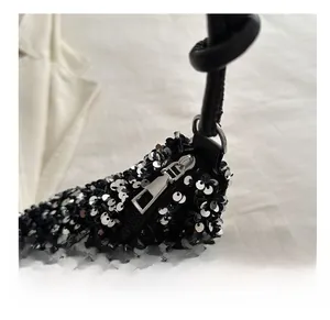 Detail of sequin bucket bag featuring a smooth metal zipper and knotted leather strap