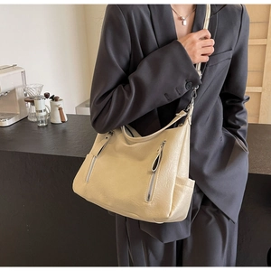 Détail d'un sac cabas en cuir souple beige avec doubles fermetures sur un blazer