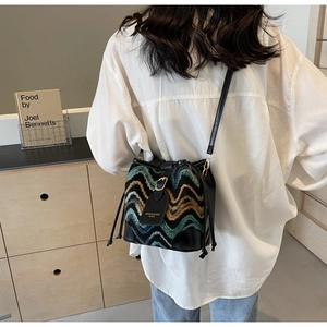 Detail of bohemian bucket bag with woven wave patterns and black leather trim