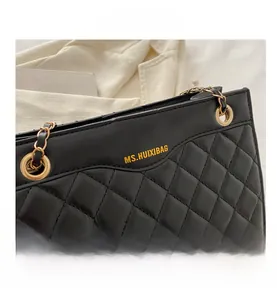 Détail d'un sac à bandoulière matelassé noir avec chaîne dorée et logo de marque