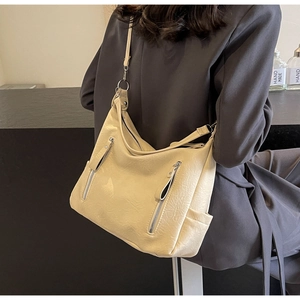 Détail montrant la texture du cuir souple plissé beige crème et les fermetures éclair