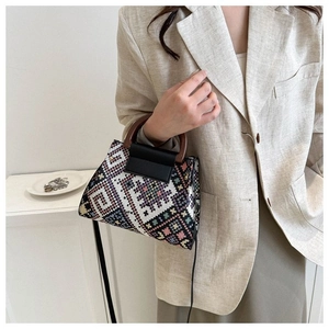 Close-up of ethnic geometric canvas handbag with wooden handle and leather strap on model
