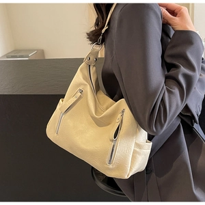 Détail du sac hobo beige avec fermetures éclair argentées et texture cuir souple porté