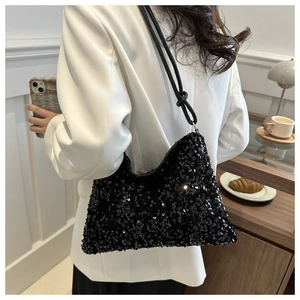 Close-up of black sequin bucket bag with knotted shoulder strap worn by a model