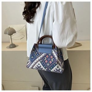 Close-up of ethnic woven handbag with natural wooden handle and leather strap detail