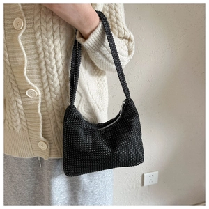 Gros plan du sac baguette à strass noirs porté par un mannequin en cardigan beige