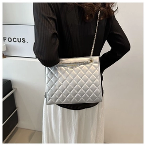 Détail macro du sac argenté matelassé avec surpiqûres en losange porté par un mannequin