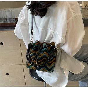 Detalle de bolso saco bohemio de punto con estampados de ondas y correa de cadena dorada