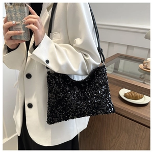 Detail of elegant black sequin shoulder bag with leather strap on white suit outfit