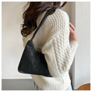 Modèle portant un sac sous le bras en strass noirs avec un pull en maille blanc élégant