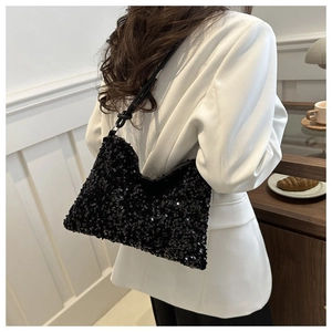 Detail of a chic black sequined bucket bag styled with a white blazer for fashion