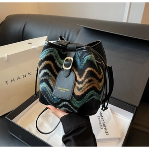 Detailaufnahme einer Boho-Strickeimertasche mit Wellenmuster und Kordelzugverschluss