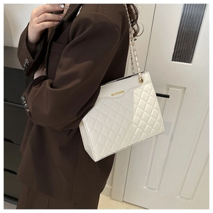 Vue latérale du sac à bandoulière matelassé blanc porté avec un blazer marron foncé
