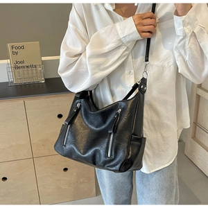 Détail du sac hobo en cuir noir avec poches zippées verticales et texture fine