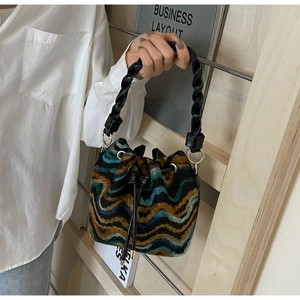 Detalle del bolso de punto tipo cubo con diseño bohemio y cordón de cuero con borla