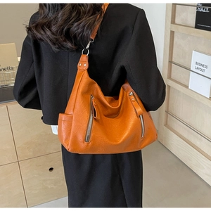 Détail du sac hobo orange vif avec texture cuir grainé et poches zippées argentées