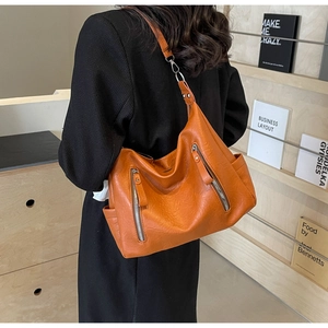 Détail du sac cabas en cuir marron-orangé avec fermetures éclair et boucle en métal