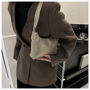 Gros plan d'un sac à main doré scintillant en strass porté avec un manteau en laine