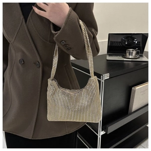 Détail du sac hobo en strass étincelants porté par une femme en manteau marron