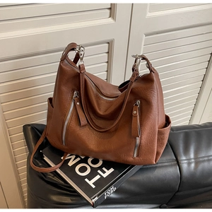 Détail d'un cabas vintage en cuir marron avec fermetures éclair et bandoulière réglable