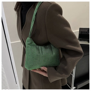Détail du sac bandoulière en strass verts avec poignée cristal sur un manteau marron