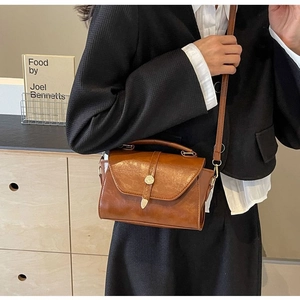 Vue détaillée de la texture du cuir ciré marron vintage sur un sac bandoulière chic