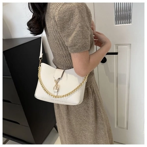 Vista lateral detallada de bolso de hombro de cuero blanco con cadena de oro y forma silla