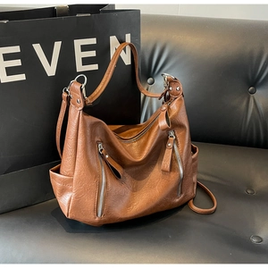 Vue détaillée de la texture du cuir marron et des poches zippées sur le sac fourre-tout