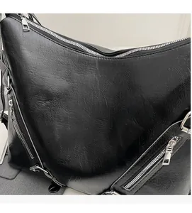 Detail shot of the black PU leather texture and functional silver zippers on the bag