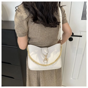 Detalle de un bolso de hombro blanco crema con hebilla dorada y cadena decorativa