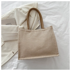 Vue détaillée du grand sac cabas en toile posé sur tissu blanc avec accessoires chics