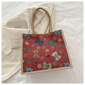 Vue détaillée d'un sac cabas bordeaux avec motifs ours et anses en lin tressé