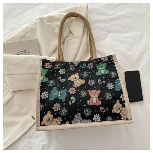 Détail du motif jacquard ours et des poignées tressées sur le sac fourre-tout noir