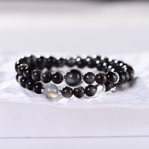 Double-layer silver obsidian bracelet with grey moonlight bead on stone pedestal