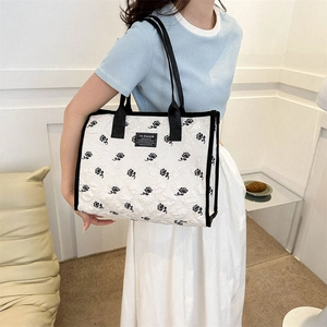 Détail du sac fourre-tout blanc matelassé avec motifs de roses noires et doubles anses